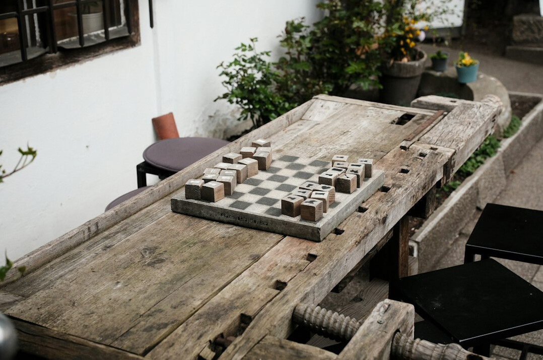 Two older men playing chess at a wooden table