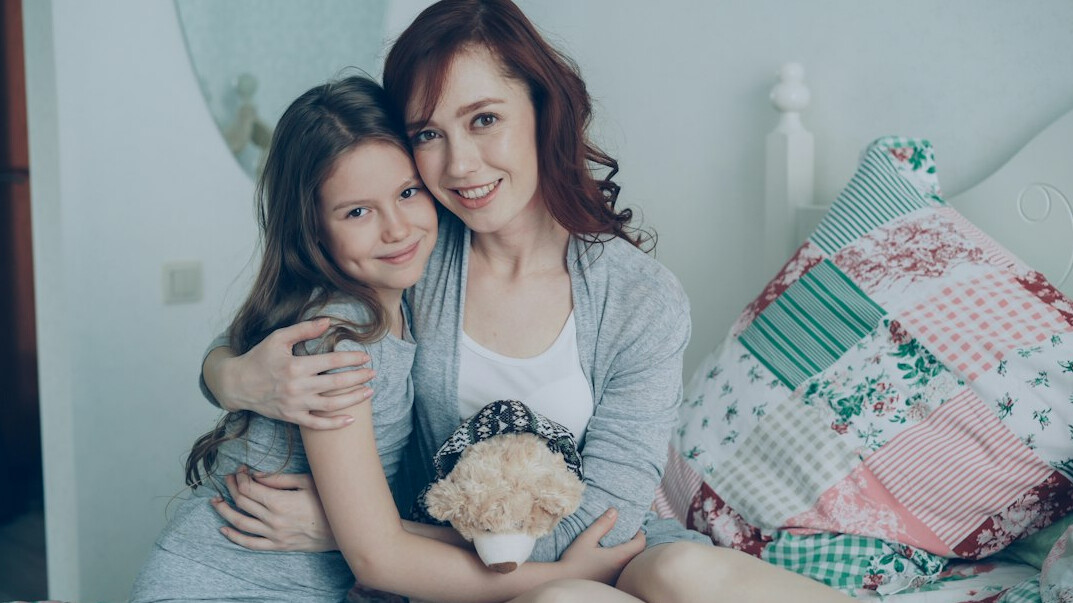 An adult daughter hugging her elderly mother at home